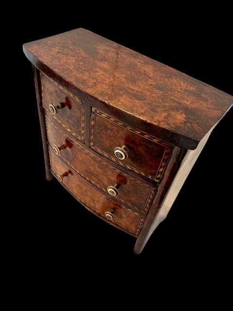 An early 19th century apprentice chest of drawers in mahogany with burr walnut veneered drawer fronts, ebony and satinwood stringing, decorative crossbanding and turned brass handles.