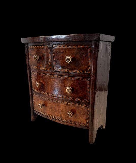 An early 19th century apprentice chest of drawers in mahogany with burr walnut veneered drawer fronts, ebony and satinwood stringing, decorative crossbanding and turned brass handles.