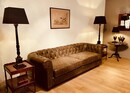 An English Green leather Chesterfield Sofa. A Pair of Antique Burr Walnut Side Tables and a Beautiful English 19th Century Pair of Lamp Stands. Classical Column Ebenised an Gilded.