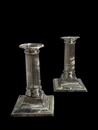 An English Pair of Edwardian Sterling Silver Candlesticks designed as fluted Classical columns on stepped square bases.